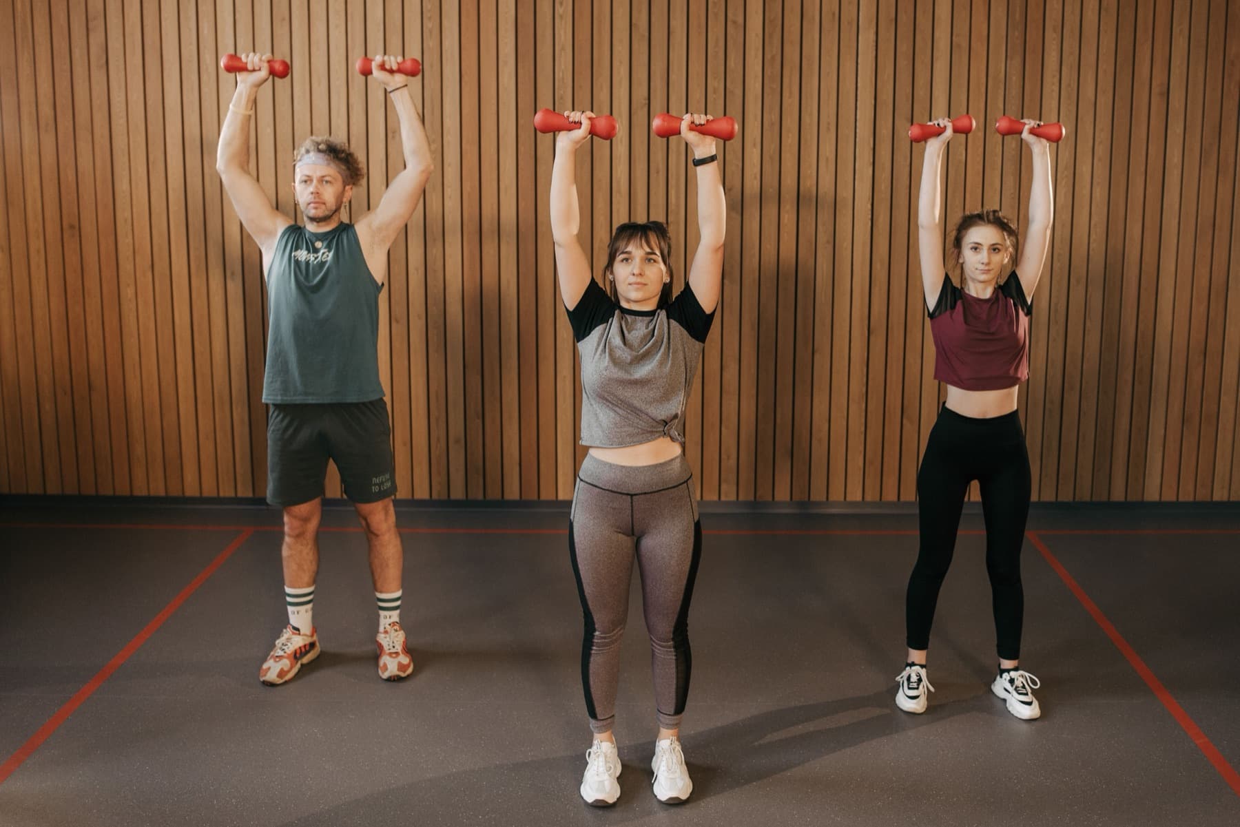 A group conditioning class pressing dumbbells overhead